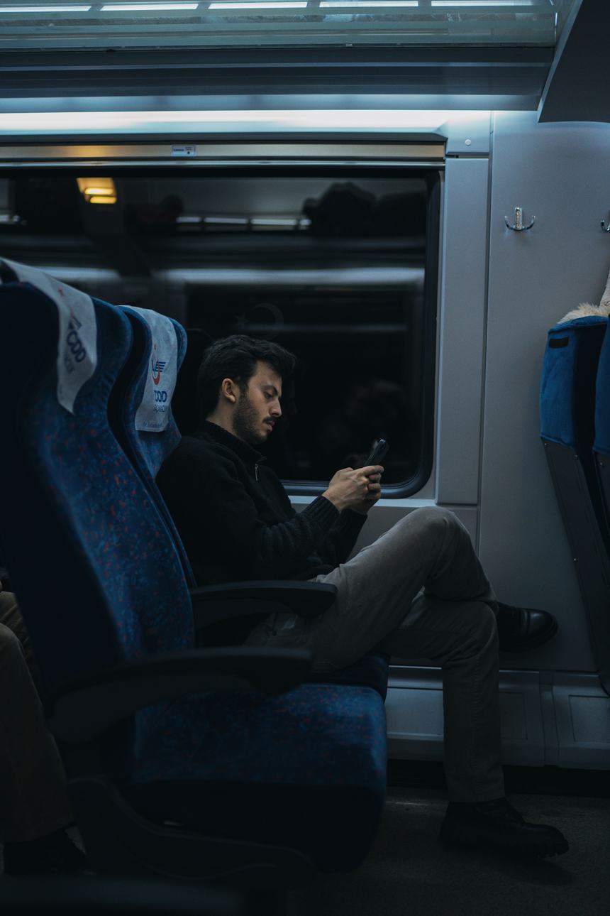 A man on a night train looking at his phone